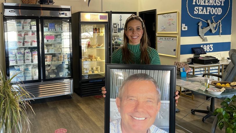 Kristen Patterson holds a photo of her dad, Tom Patterson, who is the founder of Foremost Seafood. He died on May 29, 2023. NATALIE JONES/STAFF