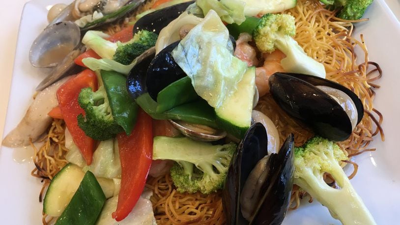 A pan-fried noodle cake topped with fresh cooked vegetables and seafood ($15) including a generous number of shrimps, scallops, mussels and clams served at Sugar & Spice Asian Bistro on Brown Street. Contributed photo by Alexis Larsen