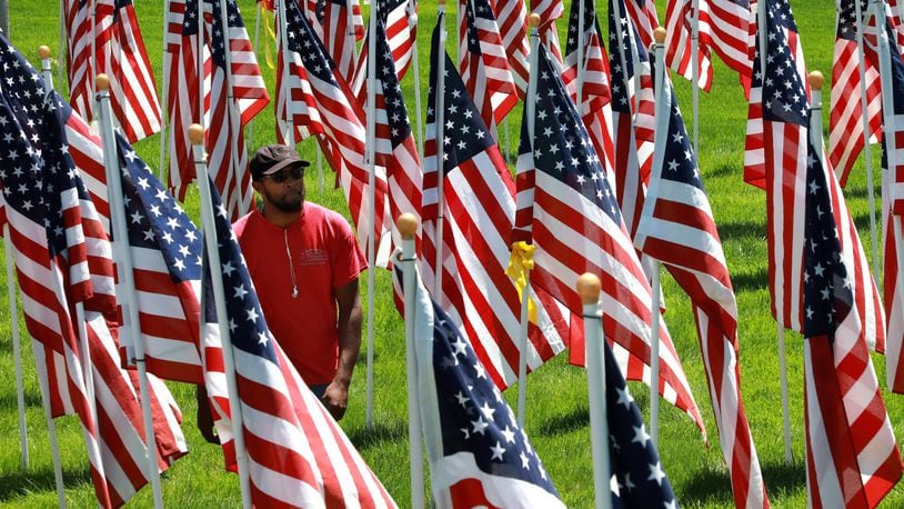 Rashad Whitaker, an employee of Natural Solutions Landscapes, takes a break from cutting grass to walk through the hundreds of American flags that make up the Field of Honor at Jackson, Lytle and Lewis Life Celebration Center Tuesday. This is the 10th year that the flags have been displayed at Jackson, Lytle and Lewis. The tribute to veterans will be on display until Flag Day on June 14. BILL LACKEY/STAFF