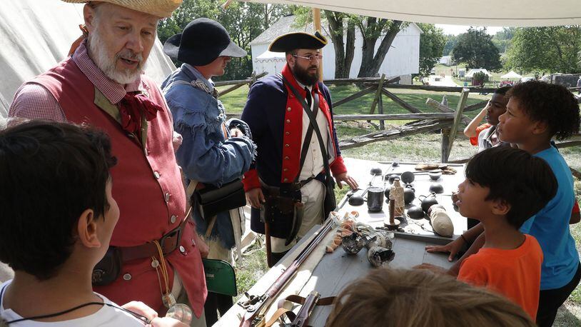 Students learn about military weapons and tactics in the 18th century Friday during Education Day at the Fair at New Boston last year. This year's festival has been canceled. BILL LACKEY/STAFF