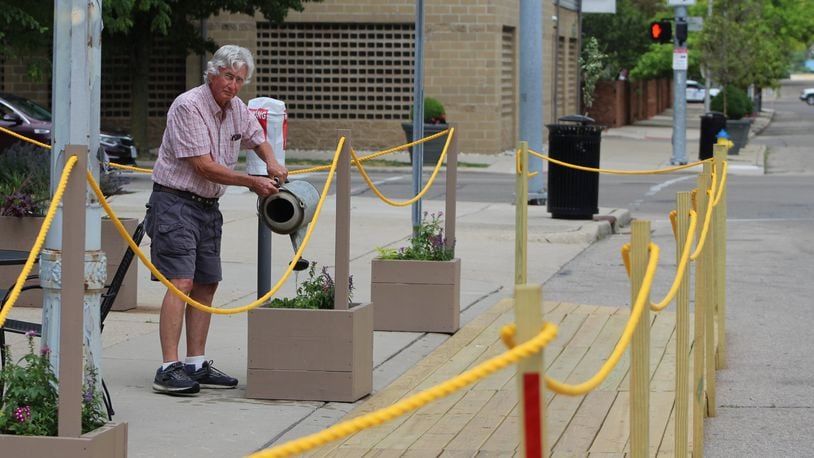 Kelly Williams, 77, waters the plants outside of Mudlick Tap House in downtown Dayton. His son, Forrest Williams, is co-owner of the restaurant, which has expanded its outdoor seating using a patio starter kit. CORNELIUS FROLIK / STAFF