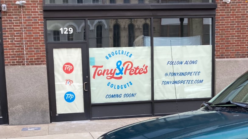 Tony & Pete's has a sign up in the Fire Blocks District in downtown Dayton, advertising for a grocery store that will also have cold cut sandwiches. KAITLIN SCHROEDER / STAFF