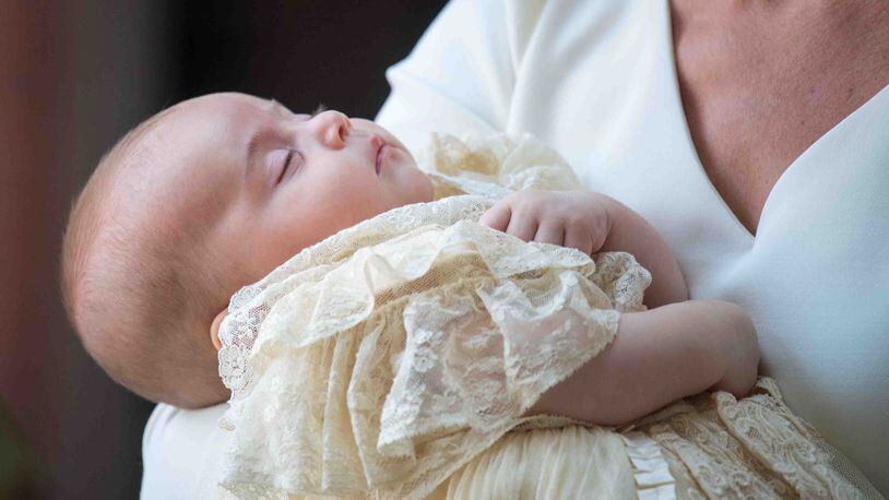 Britain's Prince Louis of Cambridge is carried by Britain's Catherine, Duchess of Cambridge on their arrival for his christening service at the Chapel Royal, St James's Palace in 2018. New photos of Prince Louis have emerged ahead of his 1st birthday.