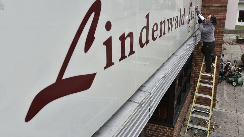 Liz Nash-Pittman removes the lettering from the Lindenwald Station restaurant Wednesday, Dec. 13. The restaurant is moving to a new location at 5072 Pleasant Ave. in Fairfield. NICK GRAHAM/STAFF