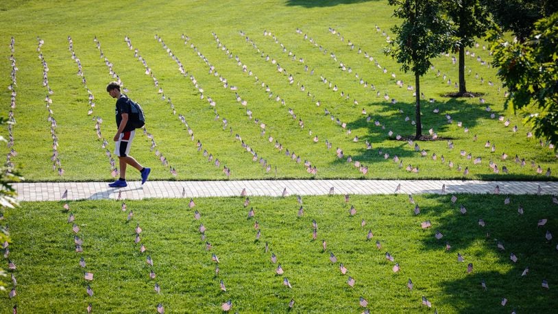 A student walks through a sea of American flags on the University of Dayton Central Mall Friday in memory of the 3,000 people who lost their lives on 9/11 20 years ago. JIM NOELKER/STAFF