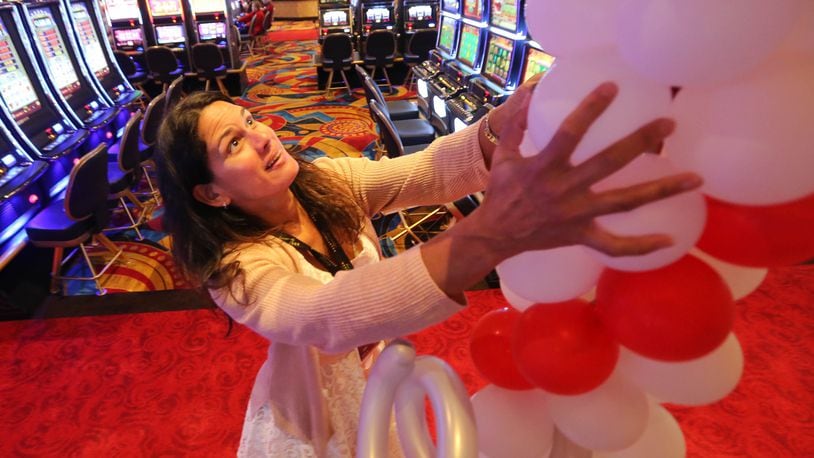 Dee Mara, marketing director at Hollywood Gaming at Dayton Raceway, sets up a column of balloons in the gaming area in preparation of the racino’s 1-year anniversary celebration event in 2015. JIM WITMER/STAFF