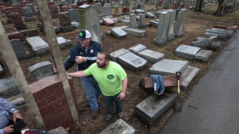 Spencer Pensoneau, center, and Ron Klump of Rosenbloom Monument Company re-set stones at Chesed Shel Emeth Cemetery in University City, mMo., on Tuesday, Feb. 21, 2017 where almost 200 gravestones were vandalized over the weekend. (Robert Cohen/St. Louis Post-Dispatch via AP)