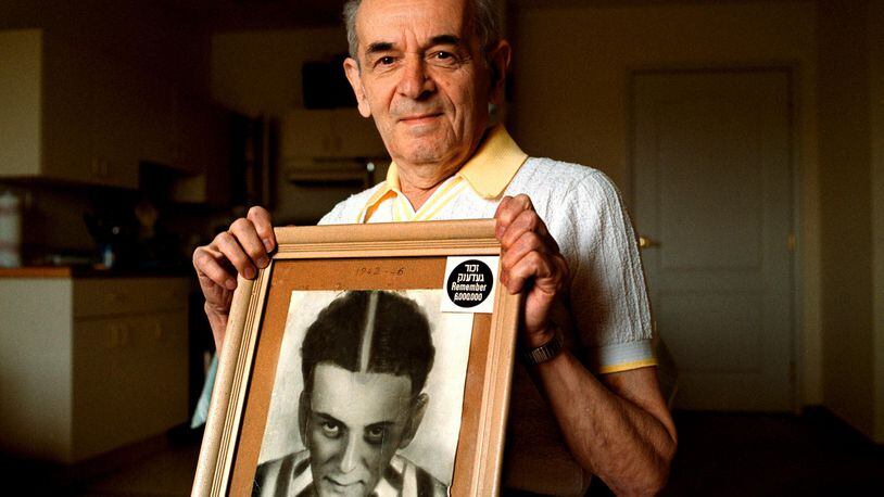 Alter Wiener holds up a photo of himself taken in July 1945, two months after he was liberated from a Nazi labor camp.