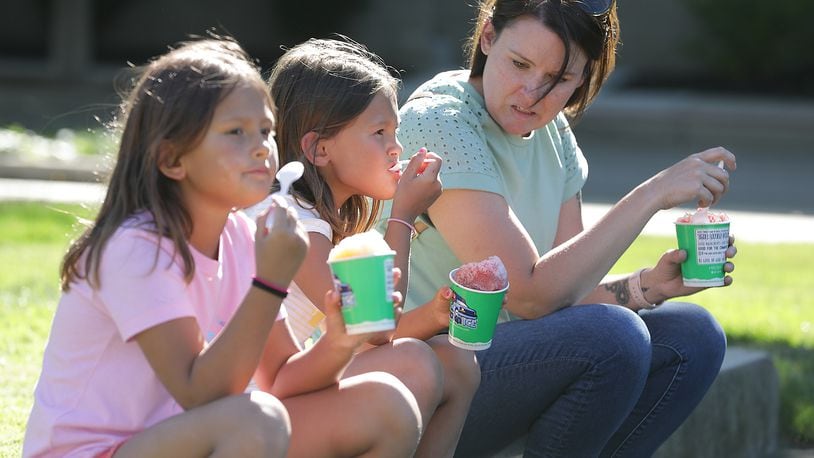 Sarah Cosby, right, enjoys some shaved ice with Penny and Phoebe Lama Thursday, June 23, 2022, during CommonsFest at National Road Commons Park in downtown Springfield. BILL LACKEY/STAFF
