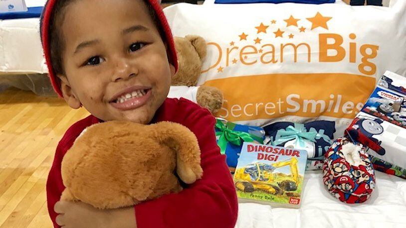 In a Secret Smiles promotional photo, a happy child sits on his new bed at one of the organizations “Day to Dream: events at the Frericks Center  on the UD campus. CONTRIBUTED