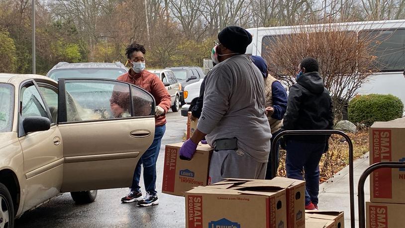 Annette Thomas, left, opens a car door so Robert Strozier, right, can place a box of food in the car at St. Luke Missionary Baptist Church in Dayton on Saturday.