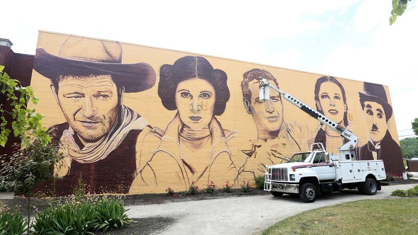 A new mural in downtown Miamisburg pays  tribute to Hollywood legends. Towering portraits - 35- feet tall - of John Wayne, Carrie Fisher, Paul Newman, Judy Garland and Charlie Chaplain have been created on the north wall of the Plaza Theatre, 33 S. Main St. Artist Erica Arndts, a Centerville native, said she wanted to âpay honor to vintage Hollywood characters,â as she put the finishing touches on the 100-foot-long mural. LISA POWELL / STAFF