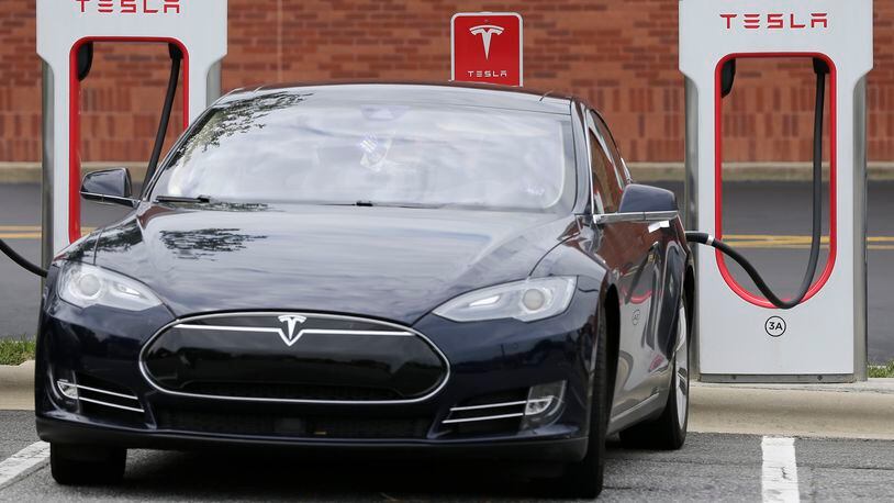 A Tesla car recharges at a charging station at Cochran Commons shopping center in Charlotte, N.C. AP Photo/Chuck Burton