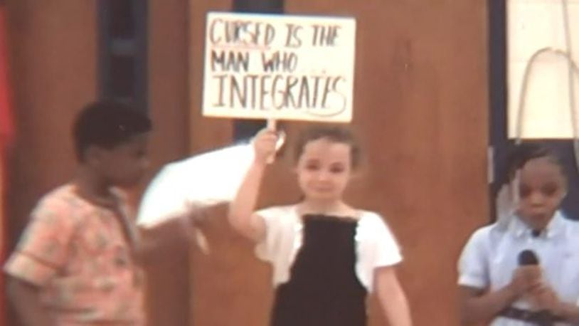 In a video of the play, Anastasia Bertram can be seen holding up a sign saying, "Please go home" on one side and "Cursed is the man who integrates" on the other side. (Photo courtesy Bertram family)