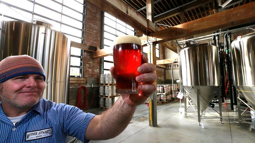 John Loftis holds up a glass of Mother Stewart’s beer to the light in their brew house in Springfield. BILL LACKEY/STAFF