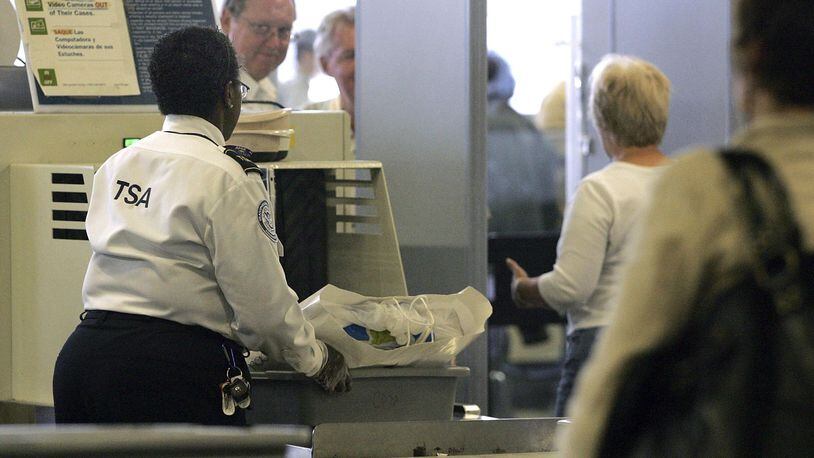 A TSA worker sends a traveler's belongings through an x-ray machine at a security checkpoint. As the partial government shutdown moves into its 25th day, more TSA workers are calling out because they're not getting paid.